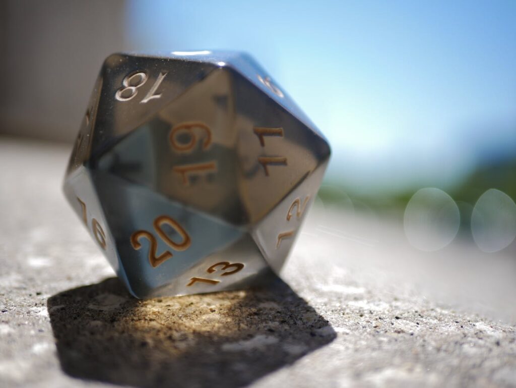 Close-up image of a polyhedral die on a concrete surface with bokeh background, capturing its three-dimensional shape and numbers.